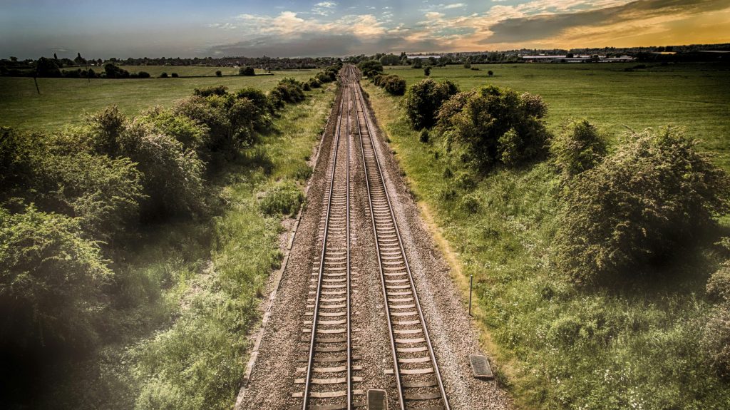 pexels-photo-533630-533630 Aerial view of railway tracks through green countryside at sunset, illustrating travel and nature.